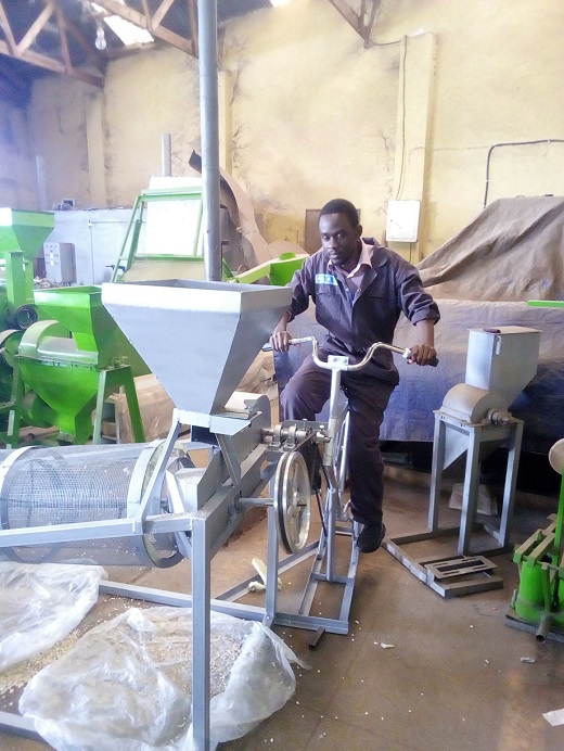 Ismael demonstrates how the bicycle-powered maize cleanign machine is operated. Photo: provided by Ismael Mayanja.